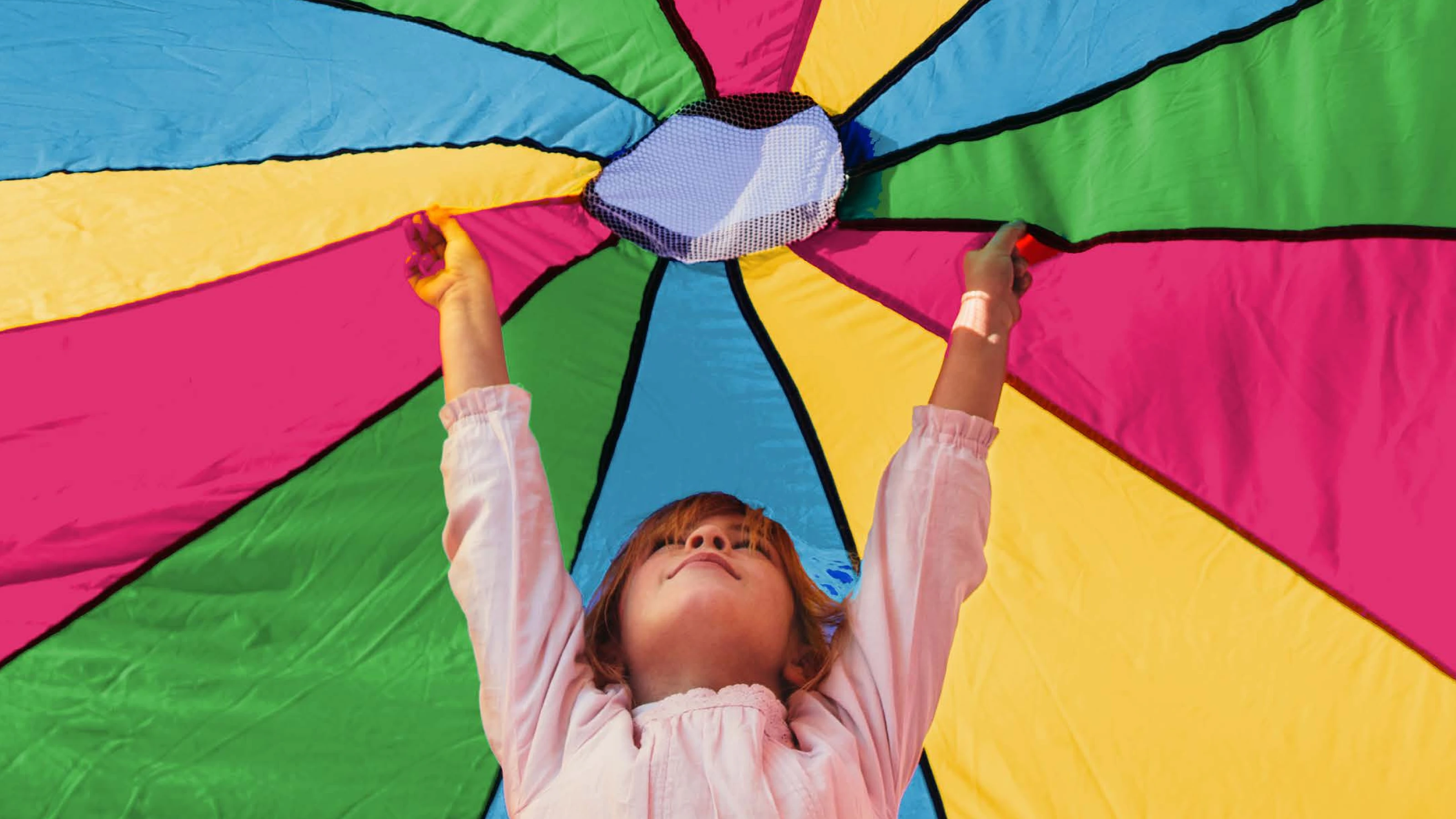 A young girl is holding up a colourful, stripy cover above her head covering her from the sun
