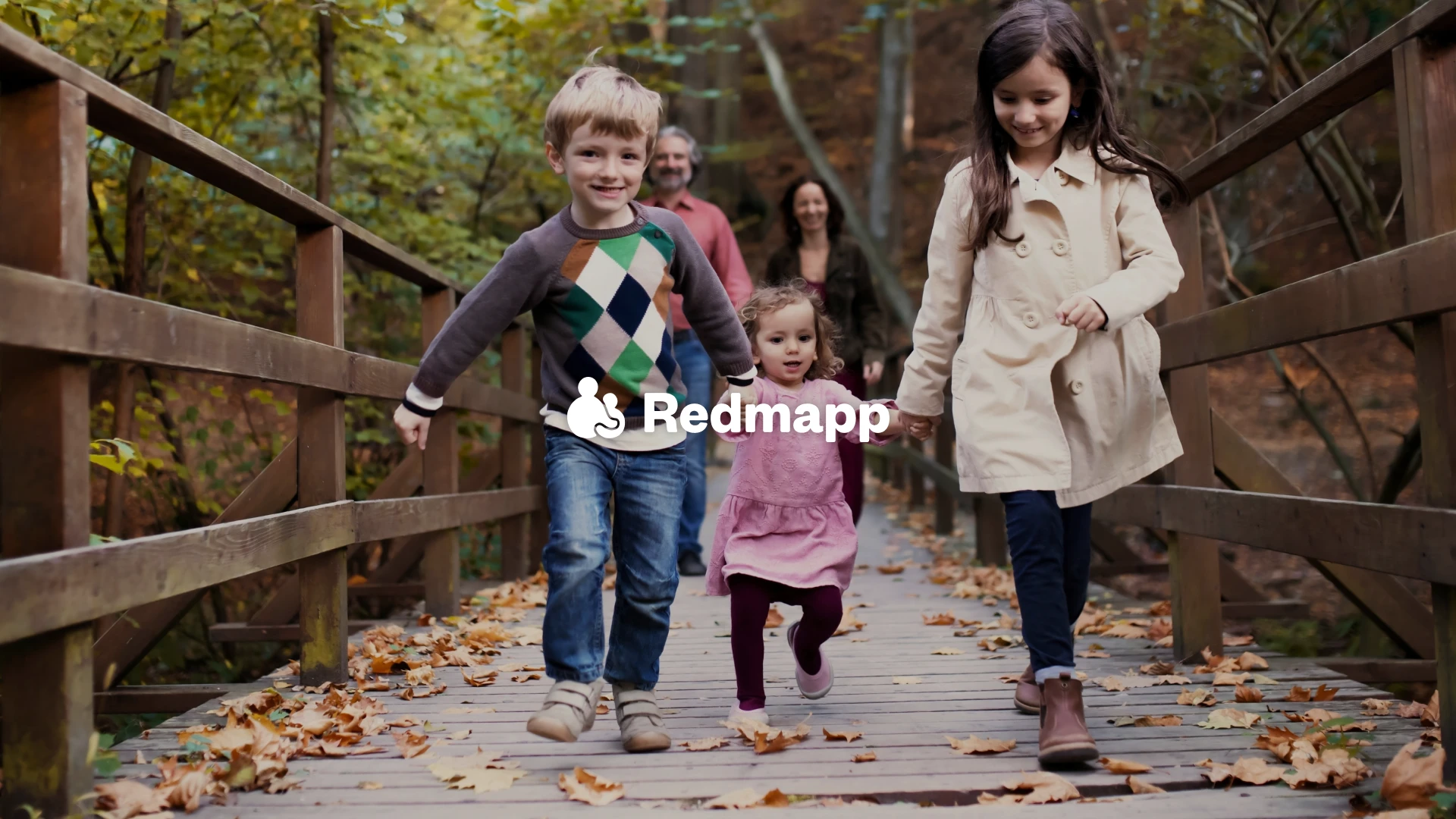 A family are smiling and holding hands as they walk forwards, the Redmapp logo is overlaid